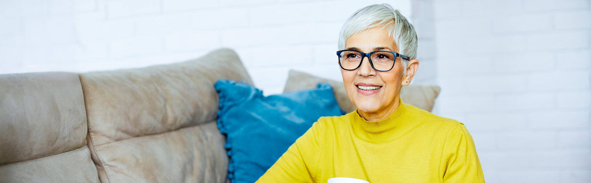 Portrait of a beautiful senior woman writing in a notebook and sitting by a sofa