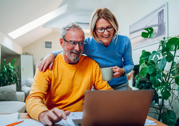 Senior couple smiling while looking at a laptop together
