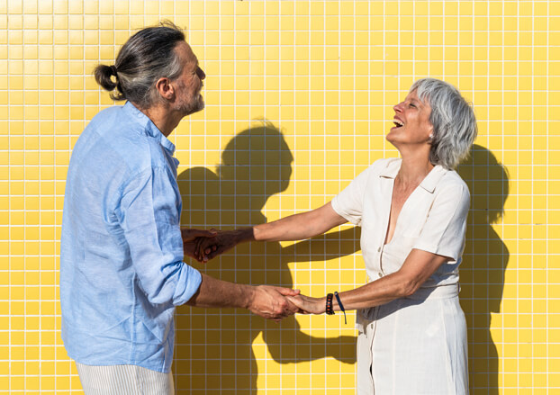Senior couple dancing in front a bright yellow wall